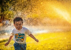 child playing in sprinkler